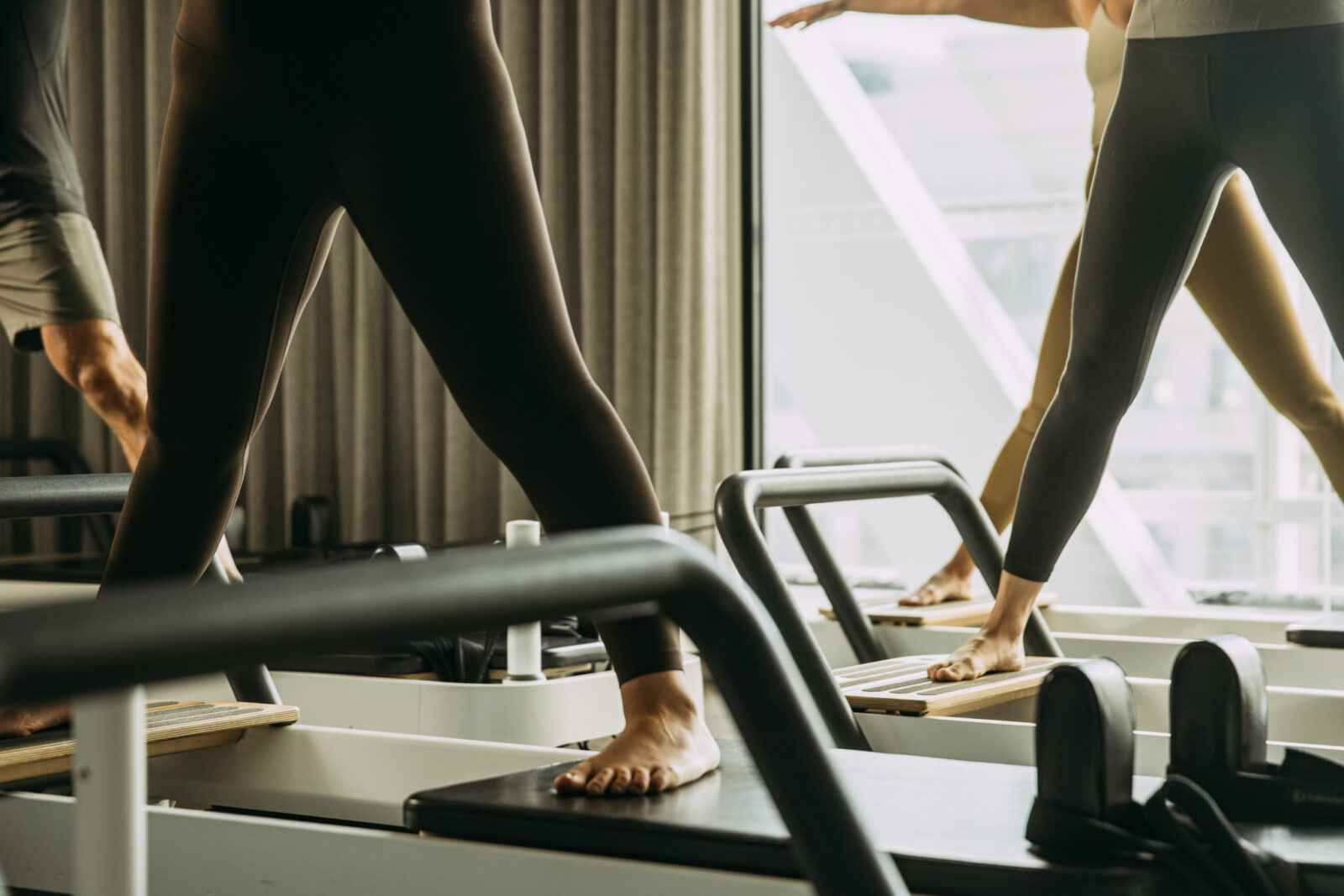 People standing wide feet a part on reformer bed