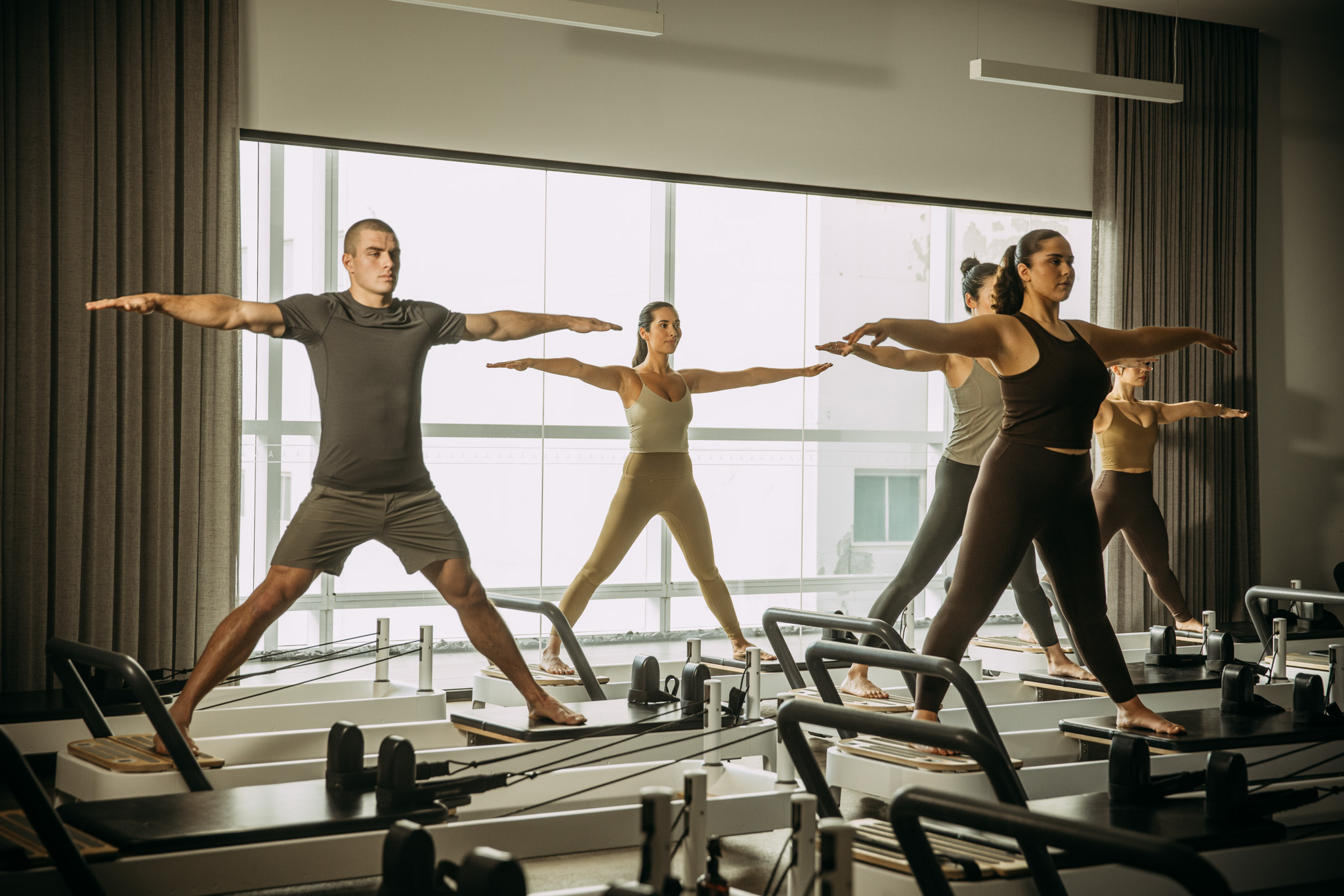 People with arms and legs wide a part on reformer bed
