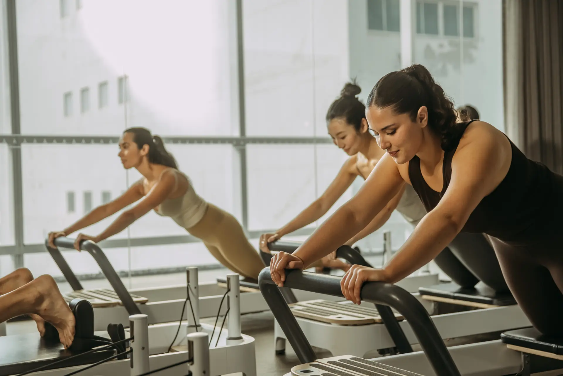 People on reformer bed holding position with arms on bar