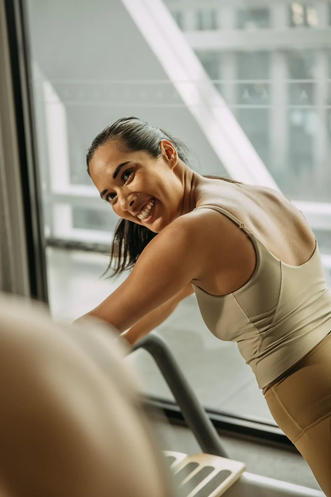 Person smiling on reformer bed holding position