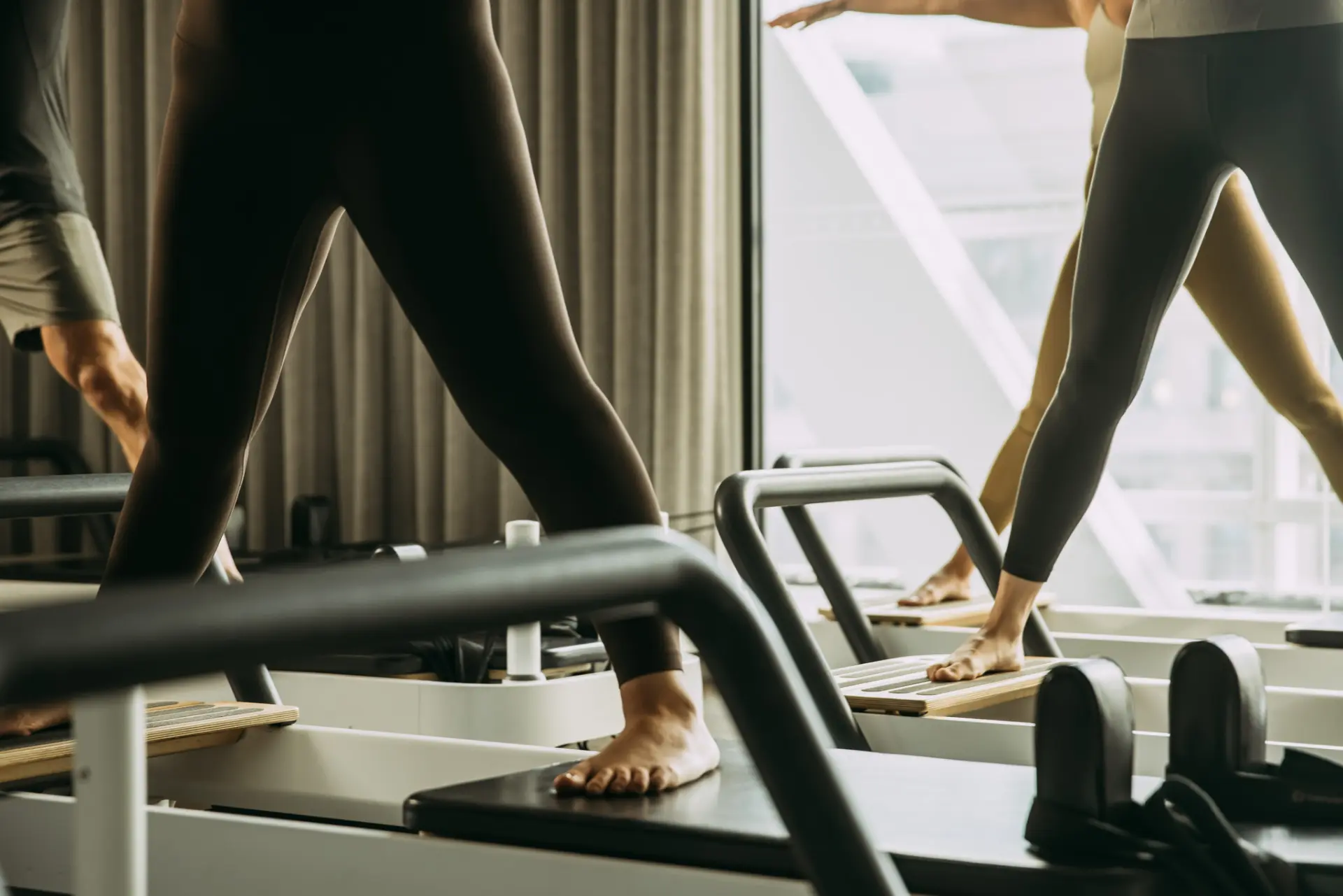 People standing wide feet a part on reformer bed