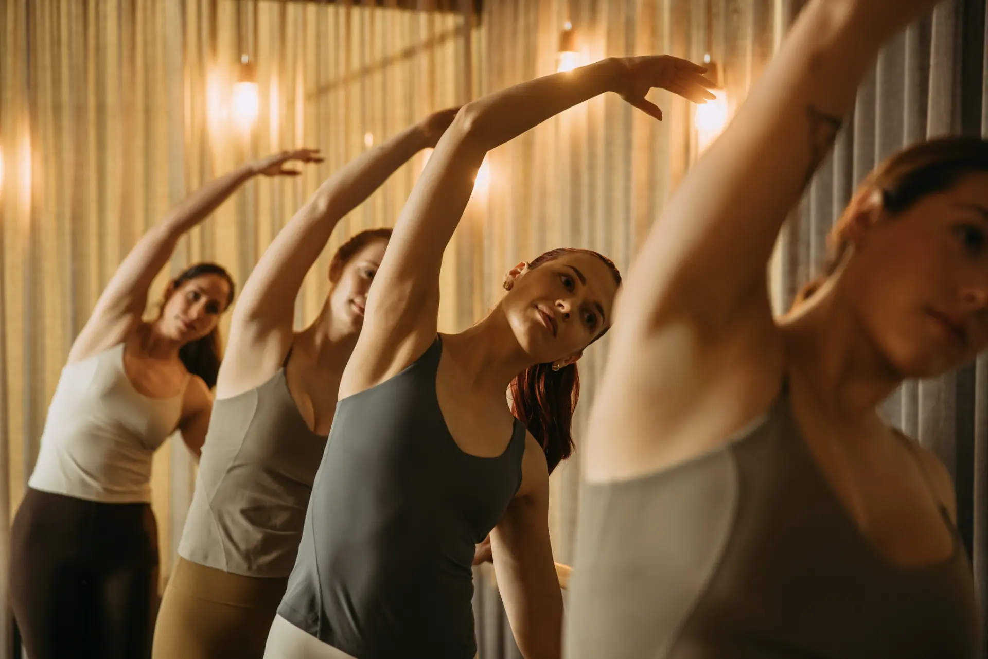 Row of people stretching arm over head holding bar